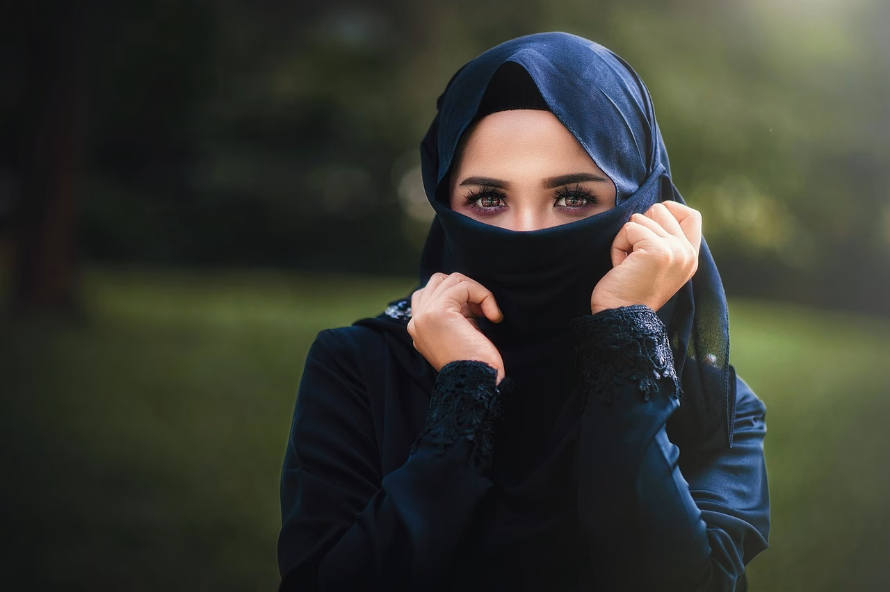 Iranilainen laulaja, hijab päähänsä kiedottuna, pitää kädessään piiskaa.