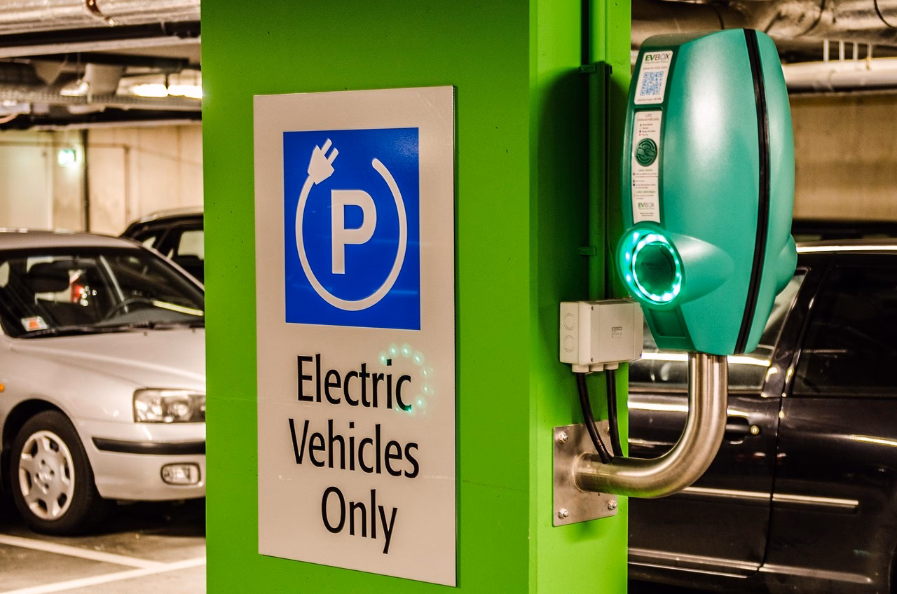 Sähköauto latausasemalla rekisteröintidokumenttien kanssa.
