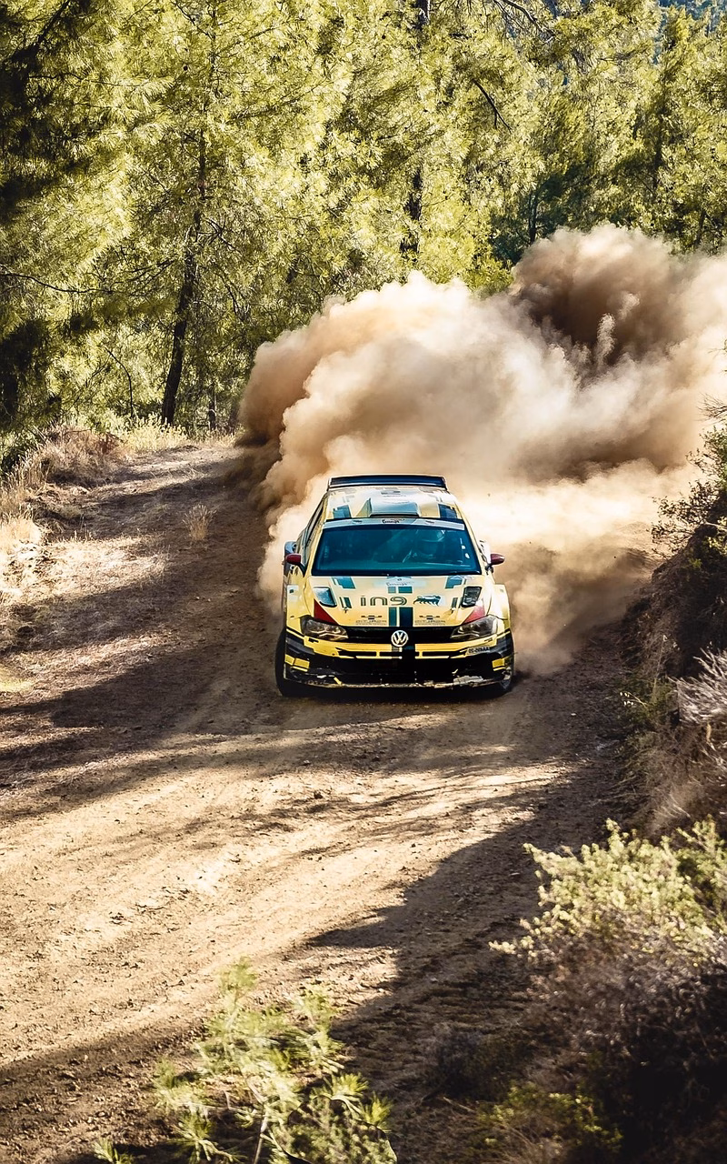 Kilpa-auto vauhdissa rallikilpailussa, yleisö seuraa innokkaasti.