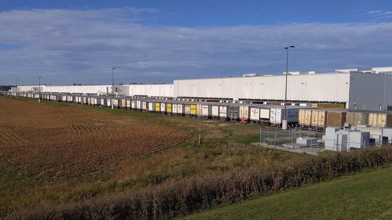 Kuljetuskuorma-autoja logistiikkavarastolla, polttoainekustannukset näkyvät taustalla.