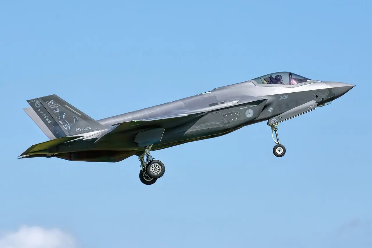 F-35-hävittäjä lentää sinisellä taivaalla, taustalla pilviä.